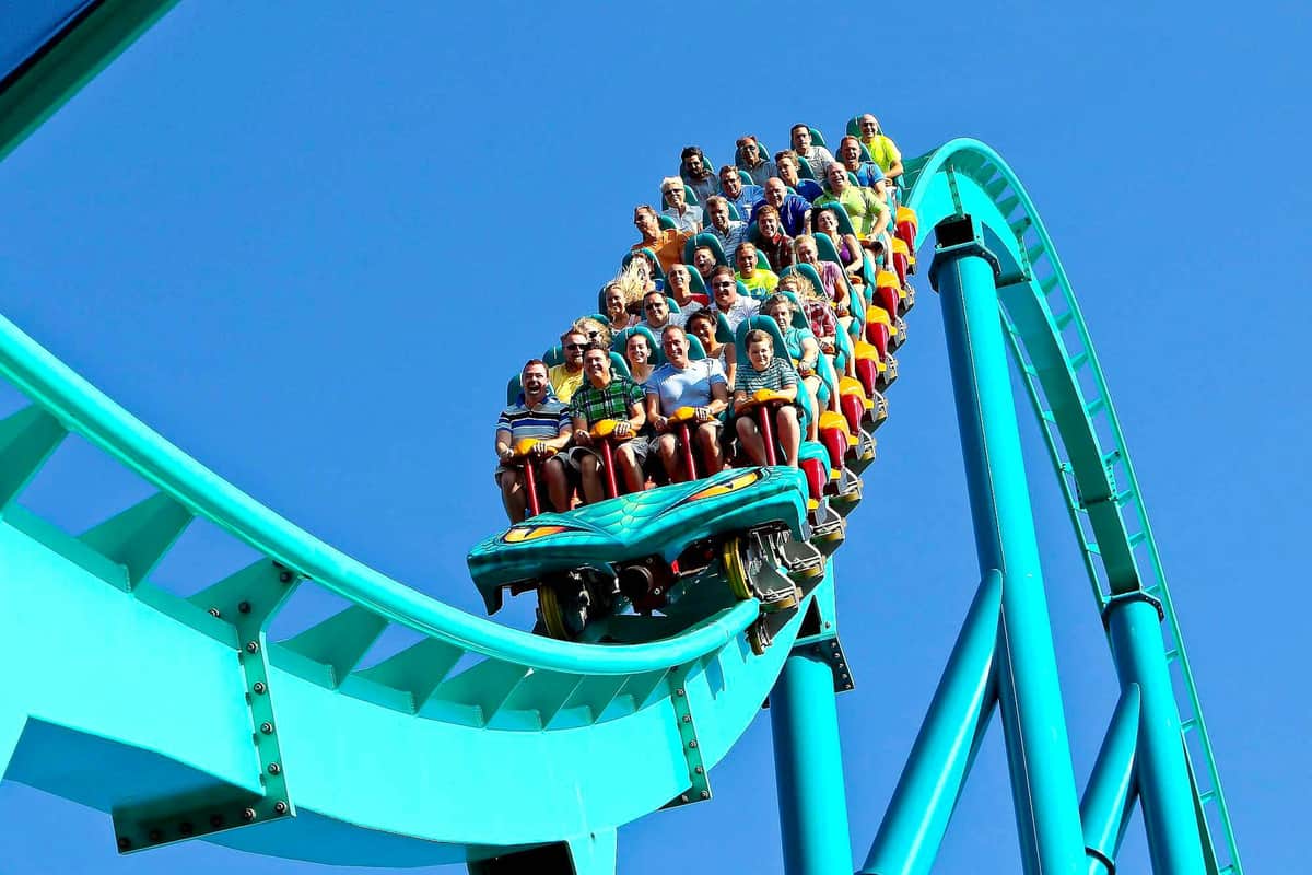 A roller coaster with riders descending a steep track under a clear blue sky.