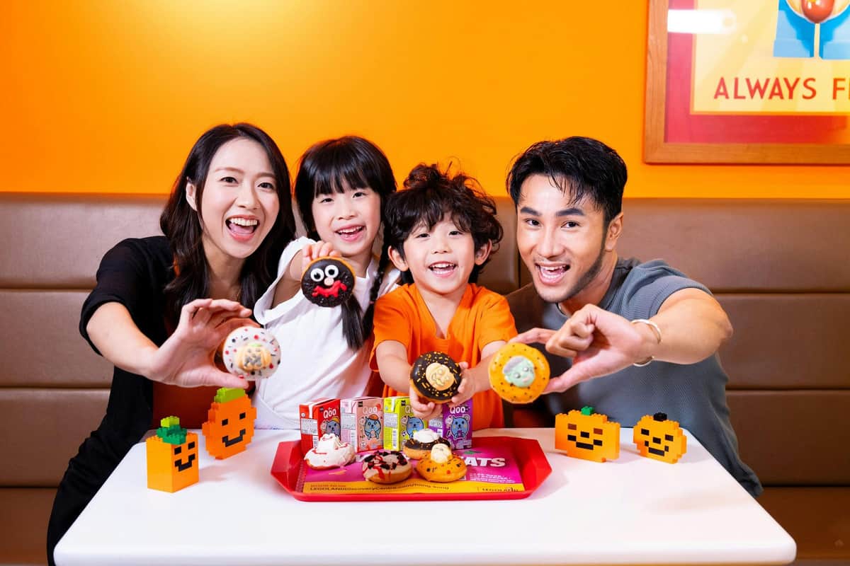Legoland Discovery Centre Hong Kong: bilet + pakiet VR Experience – Legoland Discovery Centre Hong Kong (Hong Kong) Czteroosobowa rodzina uśmiecha się, trzymając ozdobione pączki przed tacą z przysmakami i małymi dekoracjami z dyni.
