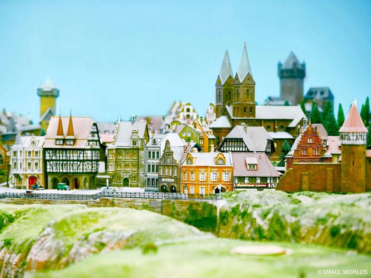 Miniature model of a European village featuring detailed buildings, a church with twin spires, and a castle in the background.
