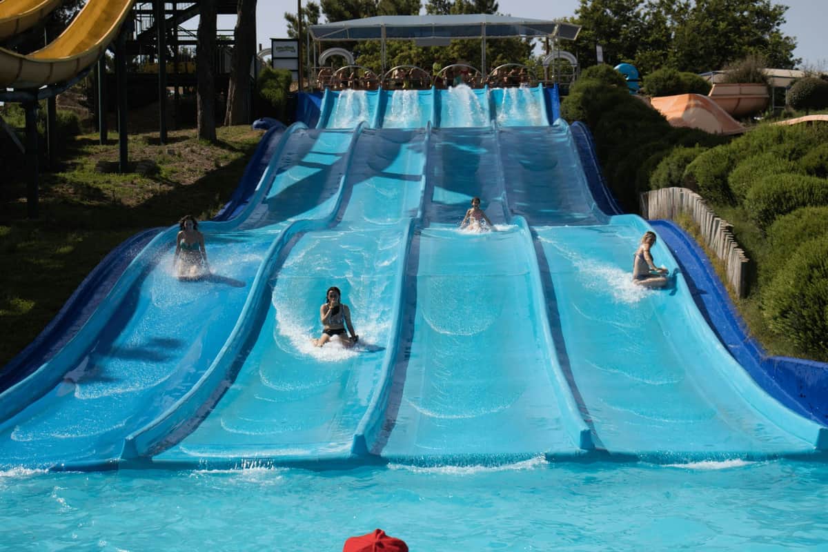 Guadalpark: Entry Ticket People sliding down parallel water slides at an outdoor water park on a sunny day.