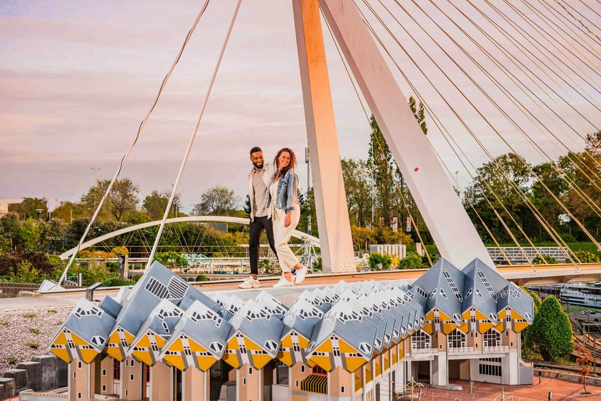 Madurodam: Entry Ticket Two people standing on a platform above a series of cubic yellow-roofed buildings, with a suspension bridge in the background.