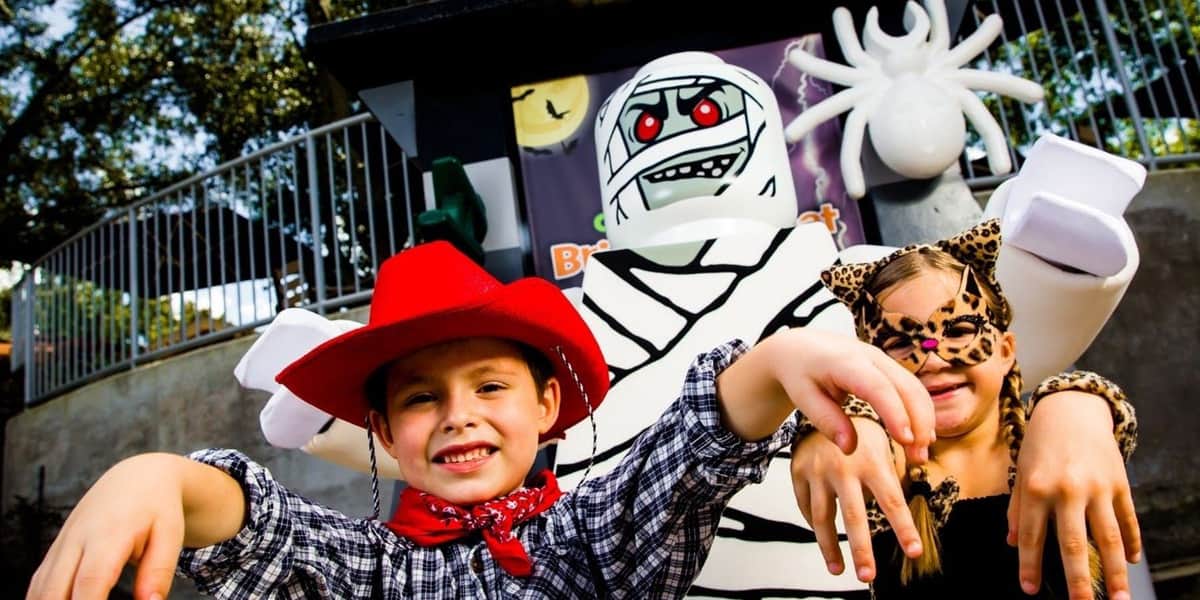 LEGOLAND® Discovery Center Michigan: Billet d'entrée Deux enfants déguisés, un cow-boy et un léopard, posent devant une décoration d'Halloween représentant une momie et une araignée.