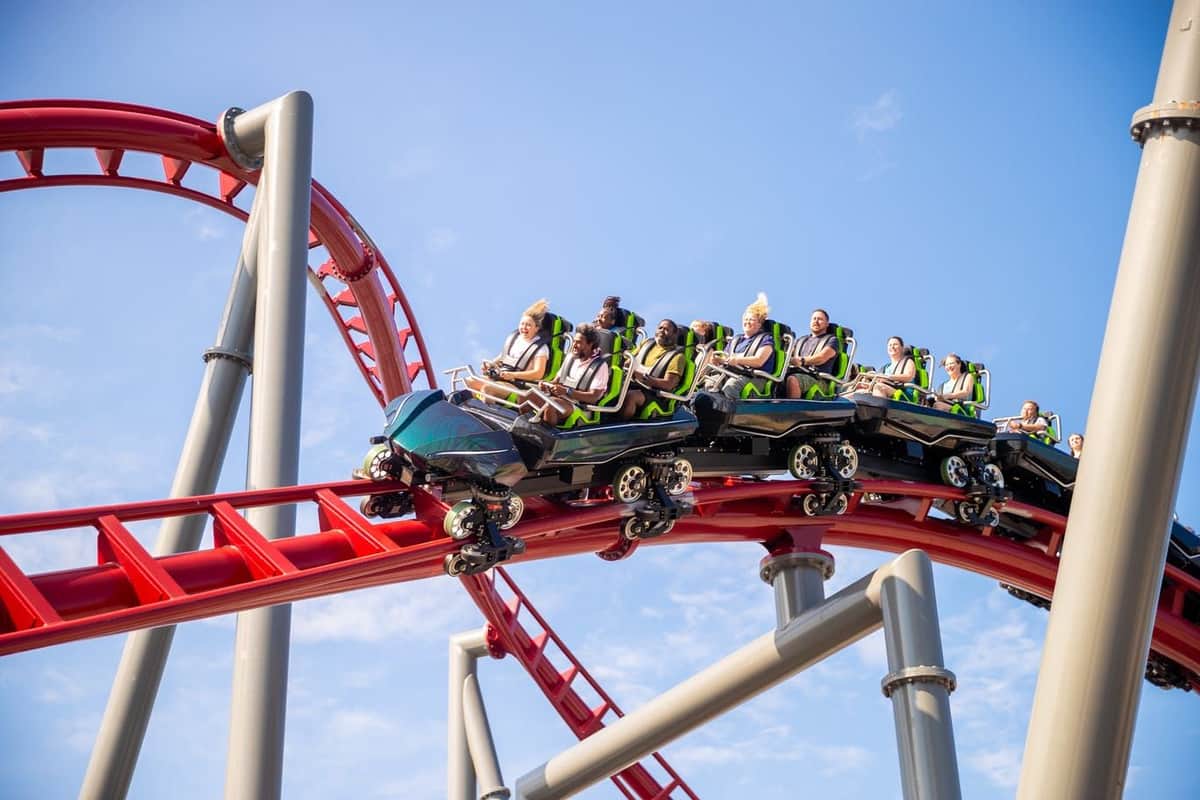 People riding a swing ride high above a coastal amusement park, smiling and enjoying the experience on a cloudy day.