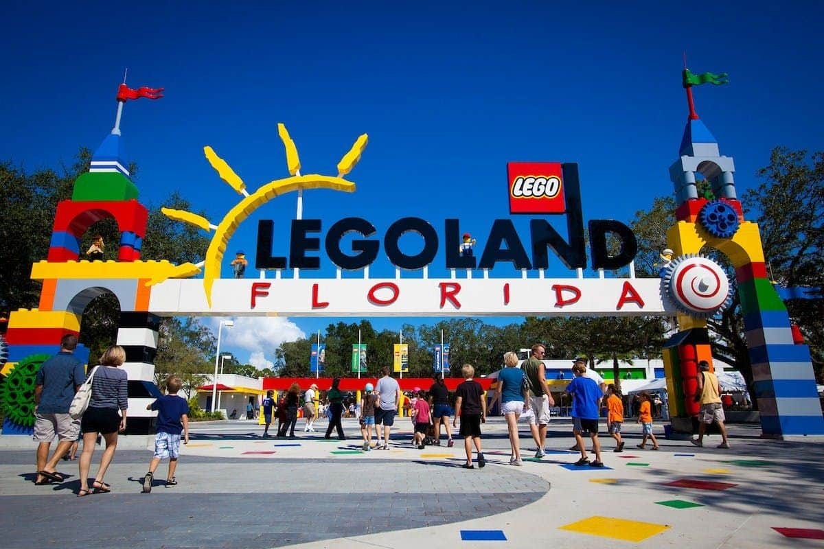 Der Eingang zum LEGOLAND Florida ist farbenfroh dekoriert und die Besucher spazieren unter einem sonnigen blauen Himmel umher.