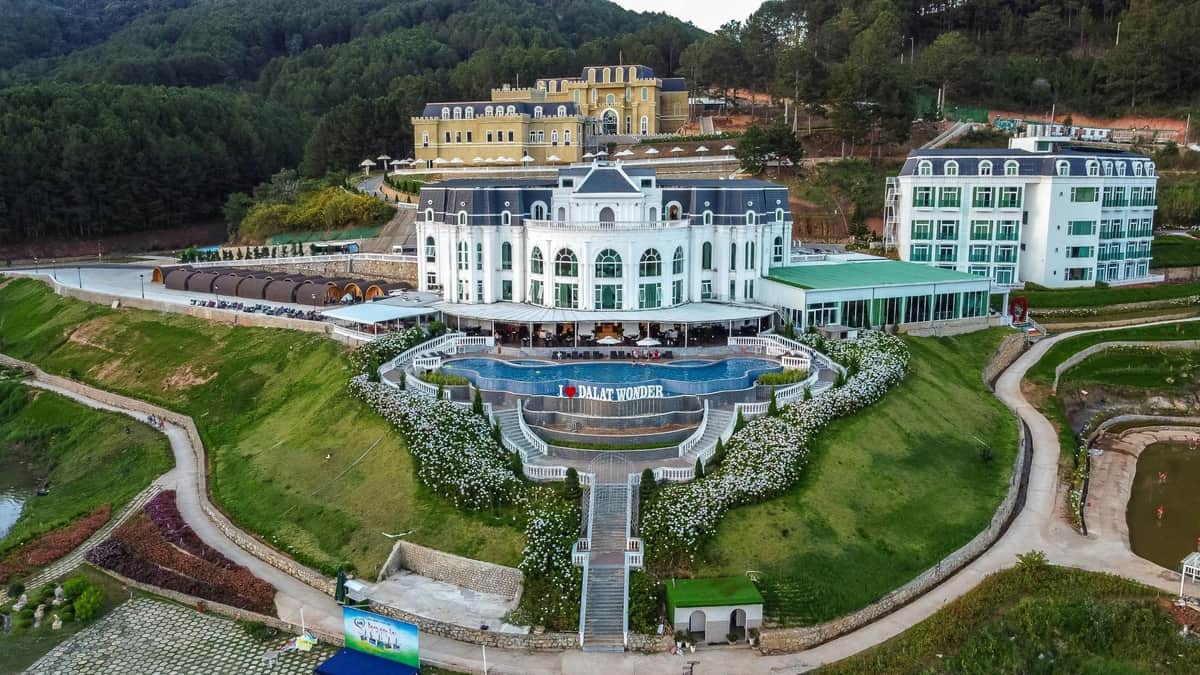 Dalat Wonderland Theme Park: Admission Ticket A grand white building with a garden terrace labeled "Dalat Wonder" and a staircase descending through landscaped greenery.