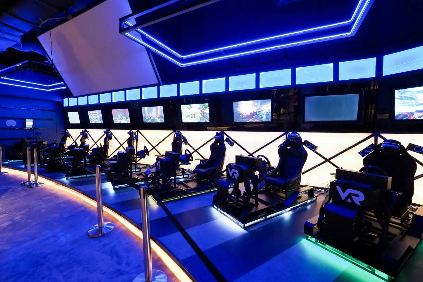 VAR LIVE A futuristic gaming setup with multiple VR seats and screens under blue lighting in a dedicated entertainment space.