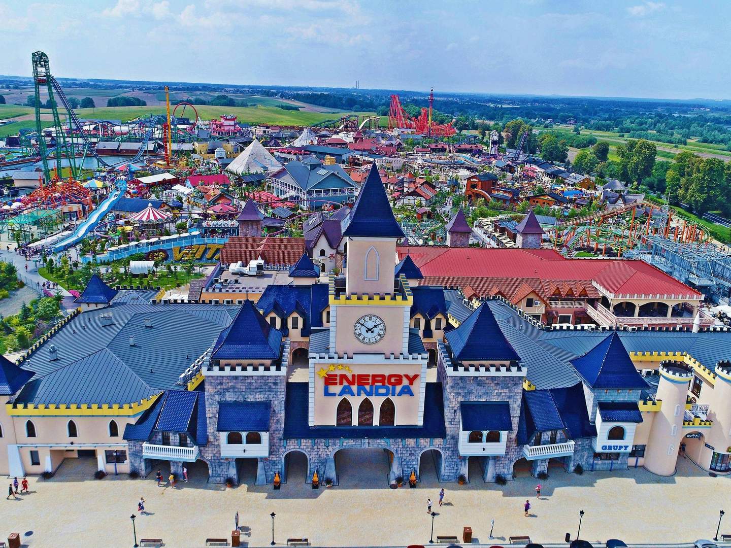 Aerial view of an amusement park with roller coasters, a water slide, and colorful buildings. Sign reads "Energylandia."