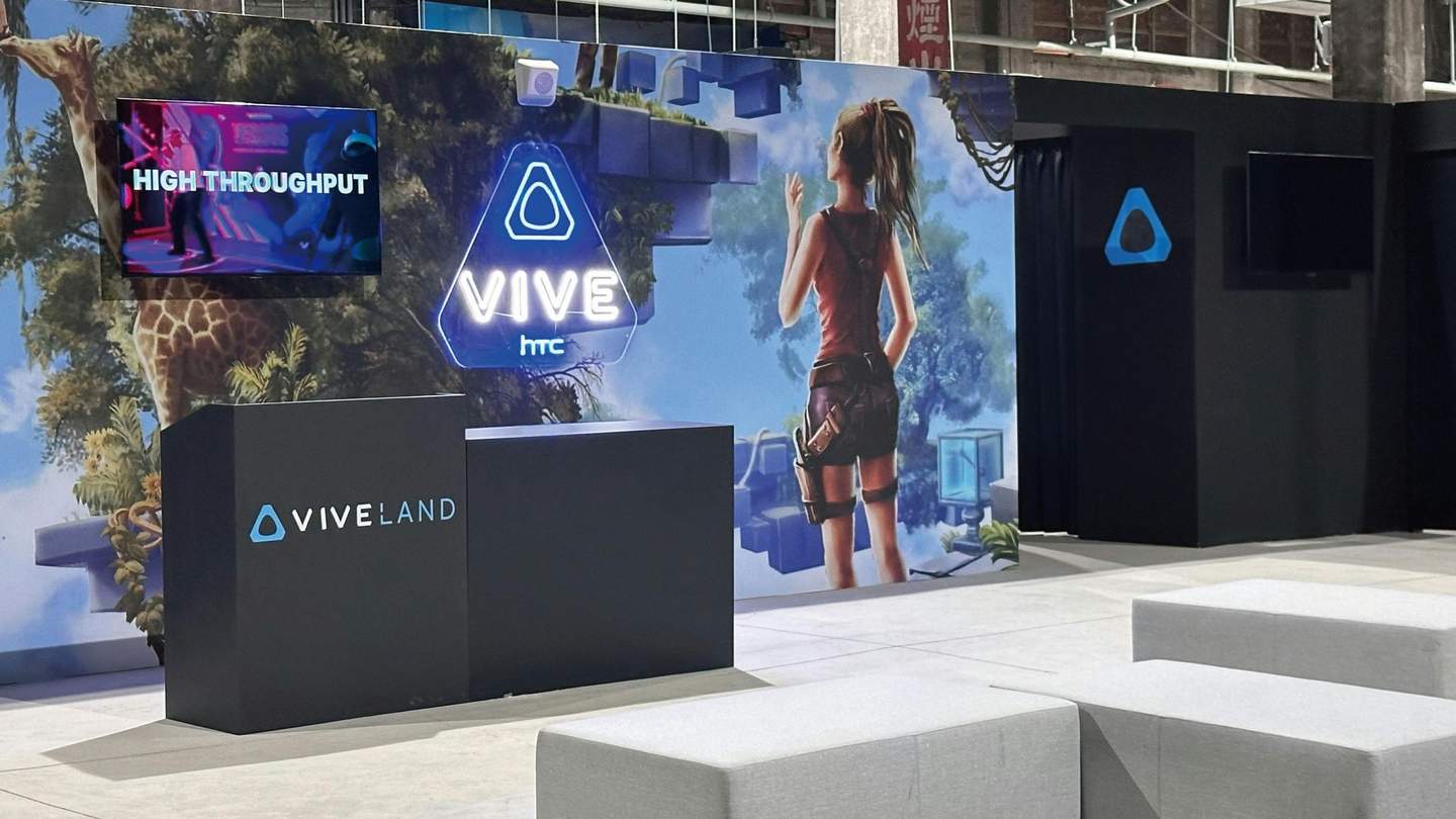 A booth setup featuring HTC Vive branding, a jungle-themed backdrop, and a screen displaying "High Throughput."