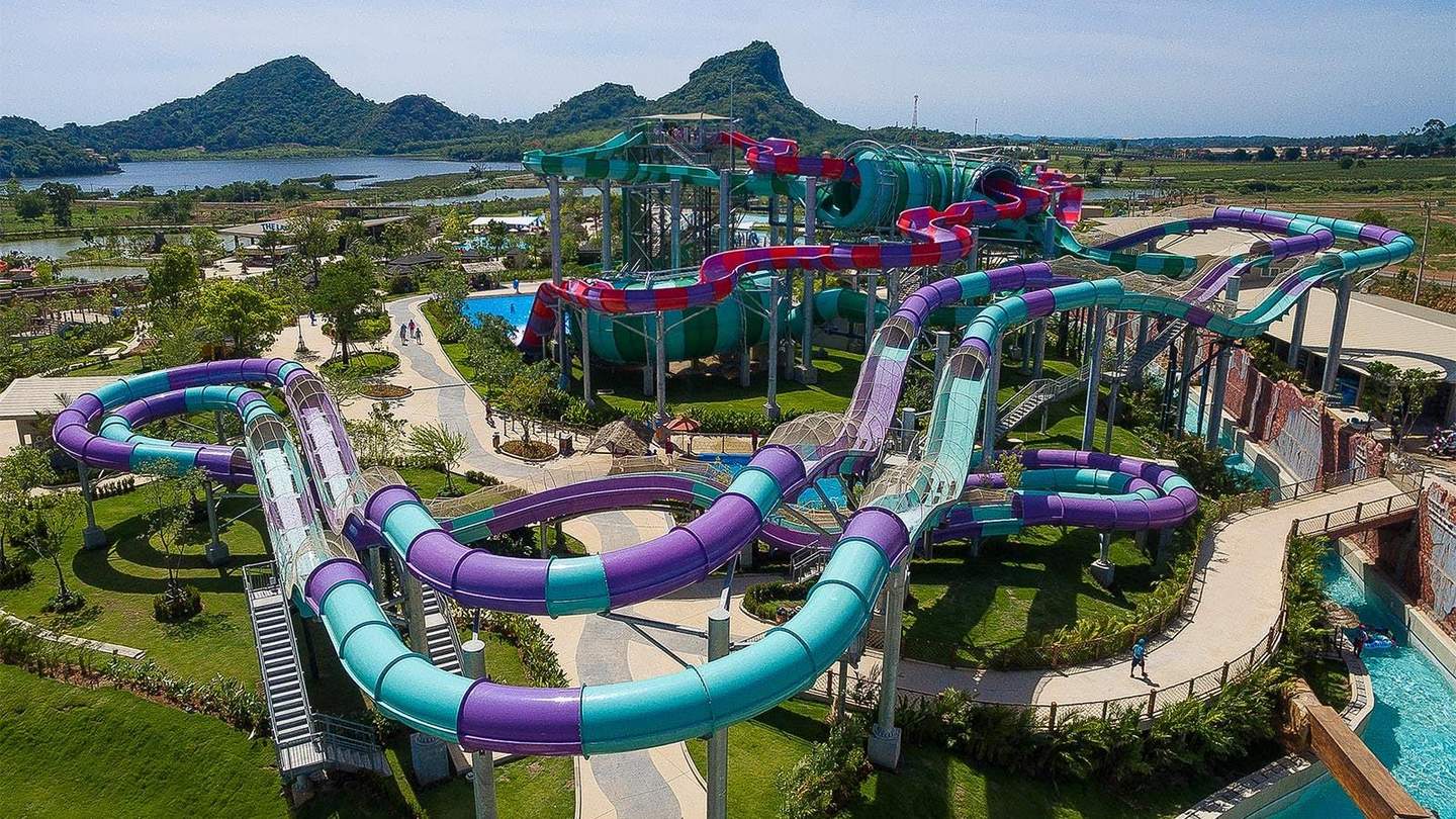 Ramayana Water Park Colorful water slides at a water park with lush green surroundings and mountainous landscape in the background.