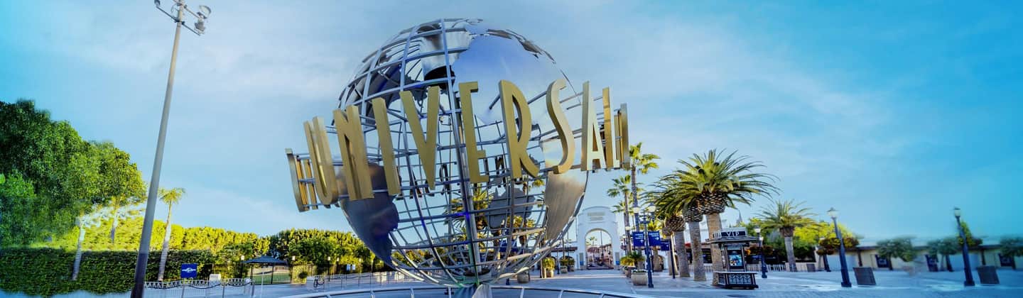 A large silver globe with "Universal" in gold letters, surrounded by trees and lampposts, stands in front of an entrance archway.