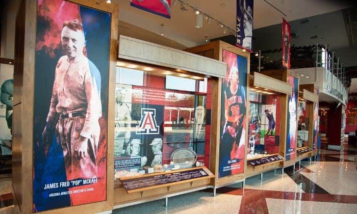Indoor display featuring sports memorabilia and large banners of athletes at the University of Arizona.
