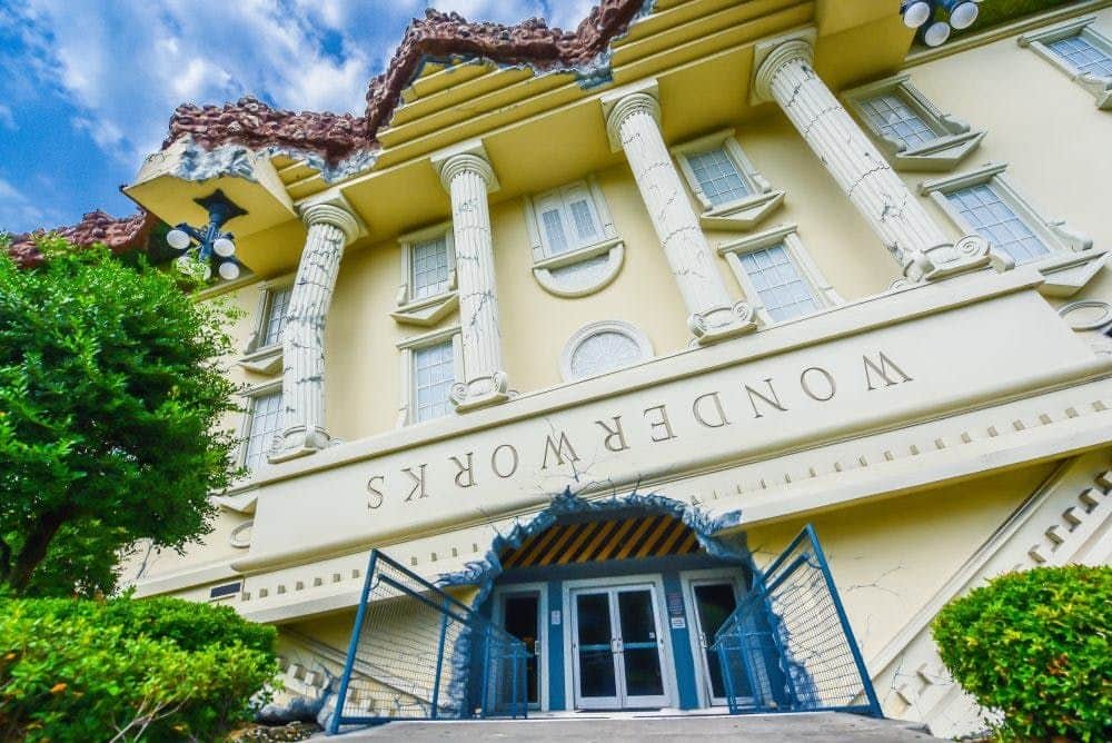 The image shows an inverted building with Greek-style columns and "WonderWorks" written upside-down above the entrance.