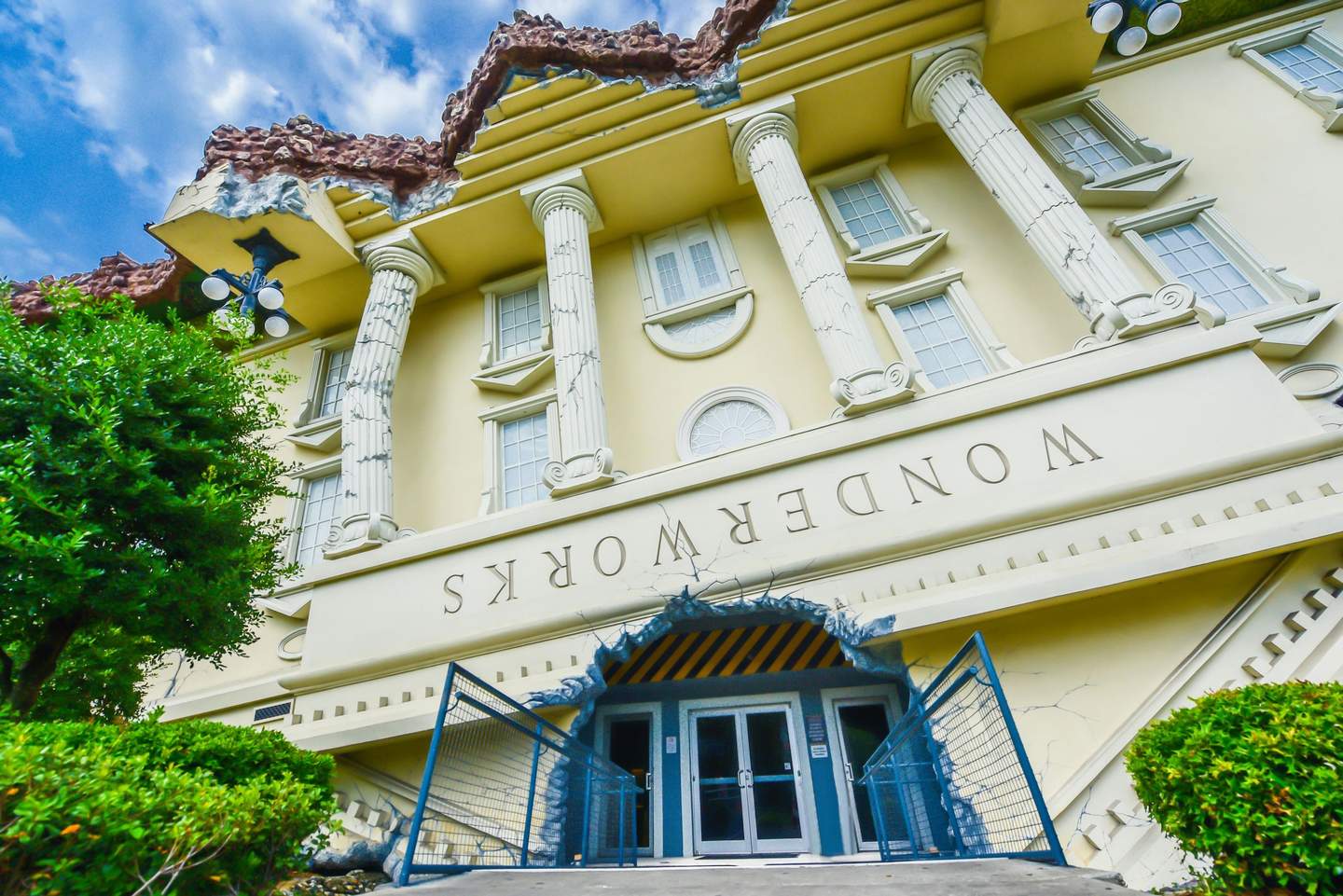 An upside-down classical building with the word "Wonderworks" appears inverted above the entrance. Trees and a blue sky are visible.