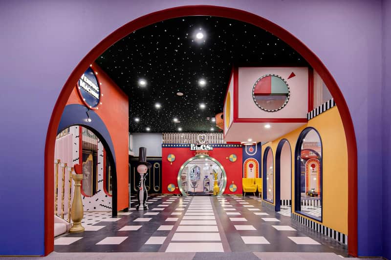 A colorful interior with starry black ceiling, geometric patterns, arched doorways, and decorative elements.