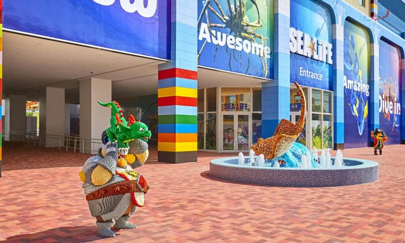 LEGOLAND Japan: Early Bird 1-Day Ticket + SEA LIFE Nagoya Entry – LEGOLAND Japan (Nagoya) A LEGO-themed entrance with a sculpture of a stingray in a fountain and a large character holding a dragon figure.
