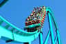 A roller coaster with riders descending a steep track under a clear blue sky.
