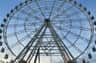 A large ferris wheel with a metal framework against a blue sky.