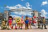 A group of cartoon character mascots, including a sponge, a starfish and a young explorer, posed at the entrance to an amusement park.
