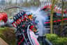 A rollercoaster with passengers riding upside down, surrounded by thematic dragon-like structures and smoke effects.