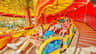 A group of people laughing and enjoying a colorful carnival ride under a yellow and red canopy.
