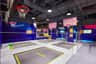 Indoor trampoline park with basketball hoops, vibrant walls, and safety netting. "Vaunce" brand visible on trampolines.