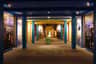 A brightly lit museum hallway with colorful columns, display panels, and a central exhibit under spotlights.