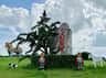 A grassy park scene featuring a large colorful horse statue, a stone with red writing, and two bear statues in regal attire.