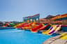 A colorful water park with various slides leading into a pool, under a clear blue sky.